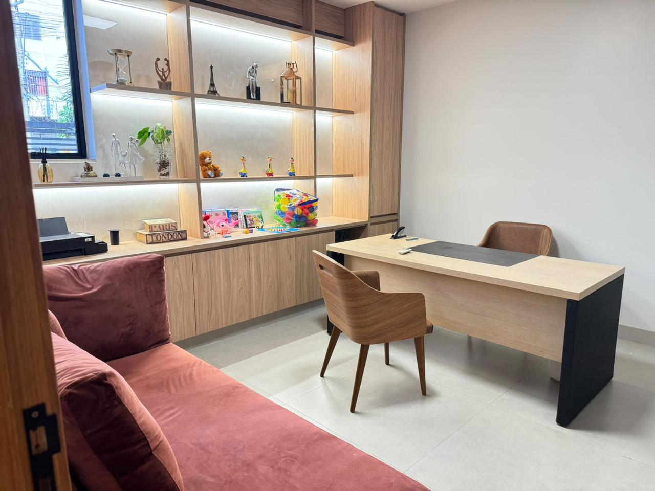 Consultório com mesa de atendimento e sofá na Aysu